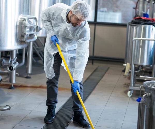 Professional industrial cleaners using equipment in warehouse facility
