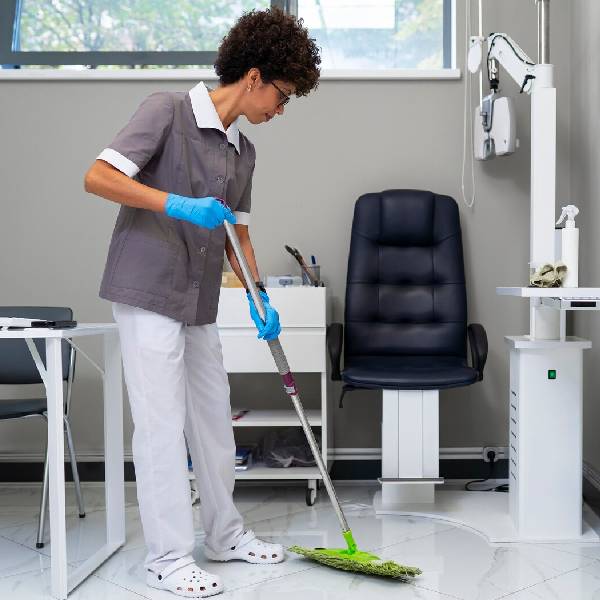 Medical clinic cleaning staff disinfecting equipment and patient areas